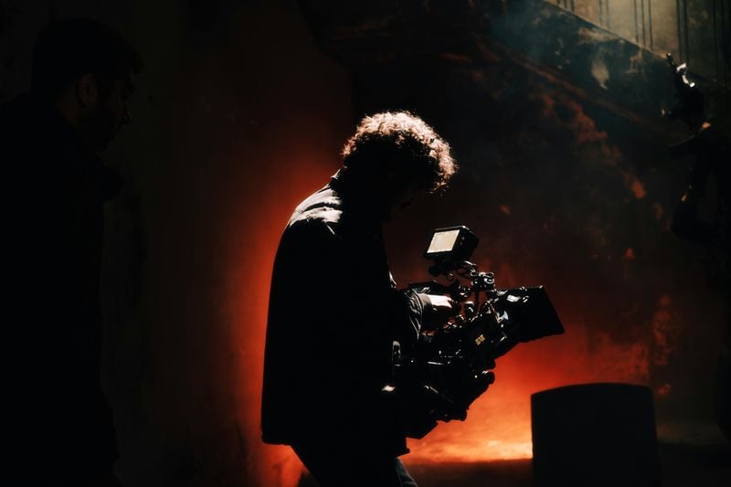 Camera operator silhouetted against warm backlight